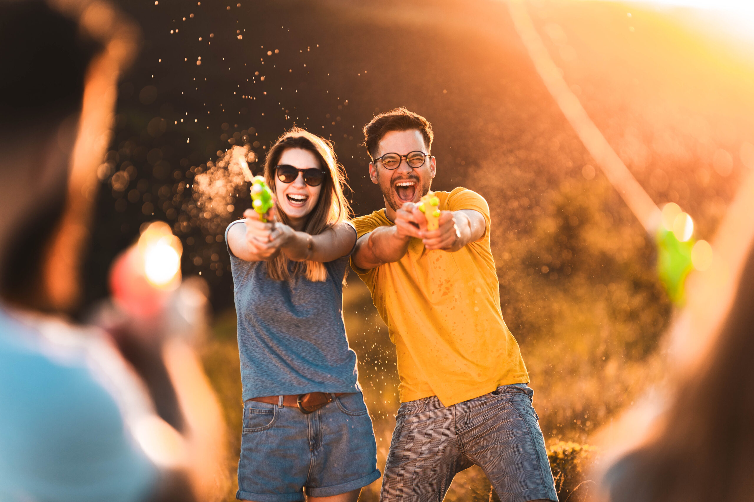 Playful couple having water gun fight with their friends in summertime.
